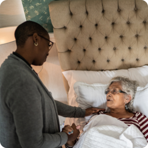 Caregiver holding hands with an elderly woman lying in bed, providing comfort and support in a warm and intimate setting.